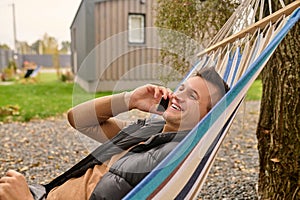 Cheerful vacationer talking on his smartphone outside