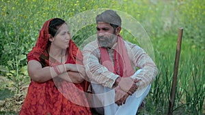 Cheerful villagers sitting in a green area talking about their agricultural work - Indian farmer family