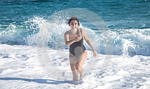 Cheerful woman in a bathing suit runs by the sea