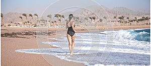 Cheerful woman in a bathing suit runs by the sea