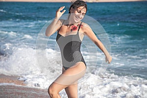 Cheerful woman in a bathing suit runs by the sea
