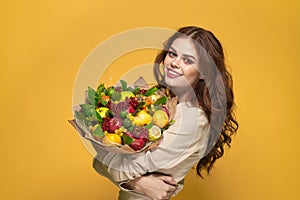 cheerful woman beige coat fruit bouquet in hands present yellow background