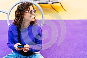 Cheerful woman browsing smartphone on playground