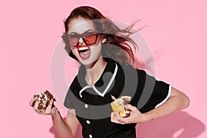 cheerful woman with cakes in hands emotions joy sweets pink background