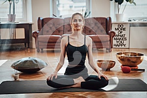Cheerful woman on carpet in lotos posture in living room