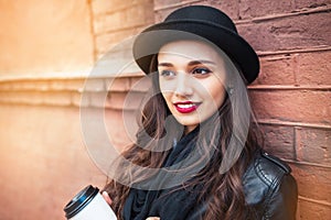 Cheerful woman in the city drinking morning coffee in sunshine light