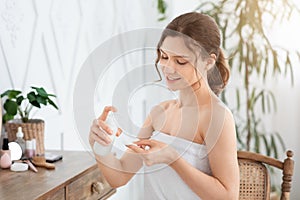 Cheerful woman cleaning her face with toner