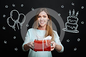 Cheerful woman coming to a party and bringing a big present