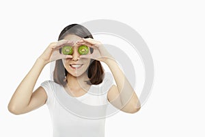 Cheerful woman covering her eyes with a kiwi