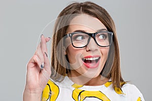 Cheerful woman with crossed fingers looking away