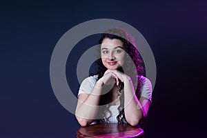 Cheerful woman with curly hair is beaming and making direct eye contact with the viewer