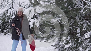 A cheerful woman dances in winter by a Christmas tree in a snow-covered forest