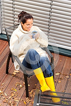 Cheerful woman drinking tea autumn rubber boots