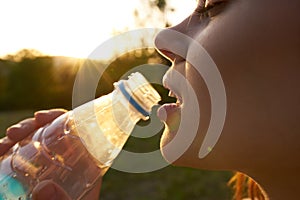 cheerful woman drinking water from a transparent bottle