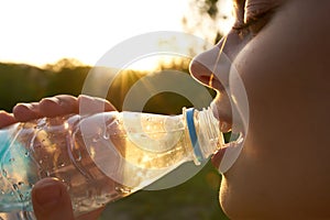 cheerful woman drinking water from a transparent bottle