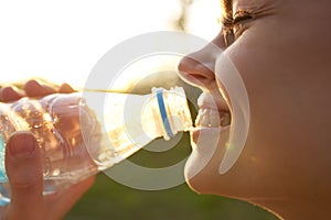 cheerful woman drinking water from a transparent bottle