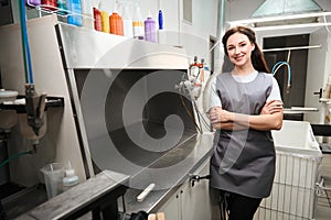 Cheerful woman dry-cleaning operator standing near workplace