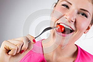 Cheerful woman eating cherry tomato