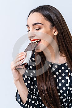 Cheerful woman eating chocolate. Cropped photo. Closeup. Black chocolate with nuts.