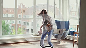 Cheerful woman is engaged in cleaning and imagines that he plays the guitar