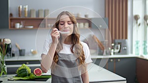 Cheerful woman enjoying food taste indoors. Young housewife smelling seafood