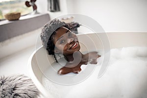 Cheerful woman feeling happy while relaxing in bath