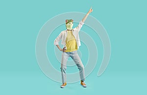 Cheerful woman with frog head shows funny dance moves having fun on light blue background.