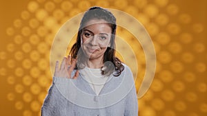 Cheerful woman happily doing salutation hand gesture, studio background