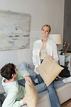 cheerful woman having fun pillow fight