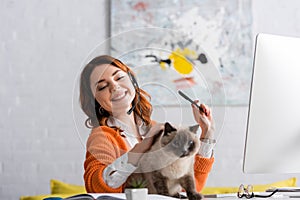 cheerful woman in headset stroking cat