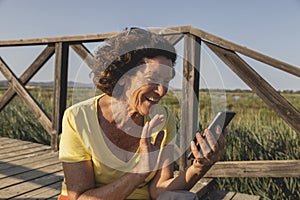 A cheerful woman, in her 70s, greets on a video call, Spain