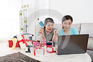 Cheerful woman holding credit card pointing laptop