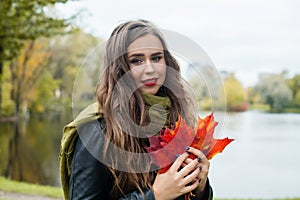 Cheerful woman holding fall leaves, autumn concept