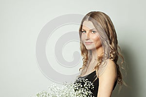 Cheerful woman holding flowers and smiling on white background