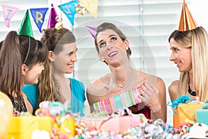 Cheerful woman holding a gift box during a surprise birthday party
