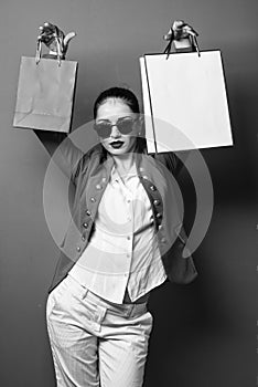 cheerful woman holding gift. portrait of an excited beautiful girl holding shopping bags over red background. woman