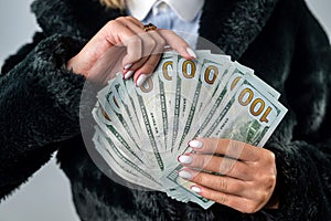 cheerful woman is holding money dollars with her fragile hands isolated on a plain background