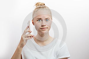 Cheerful woman holding smartphone and looking at camera over white background
