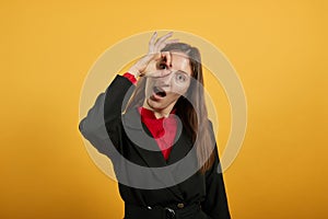 Cheerful Woman Holds Fingers To Eye As A Sign That Everything Is Ok With Her. photo