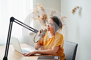 Cheerful woman host streaming his podcast using voice microphone
