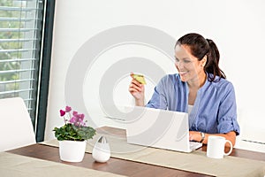 Cheerful woman internet home banking card laptop