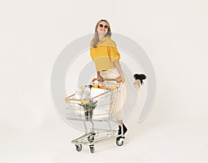 Cheerful woman leaning on shopping cart