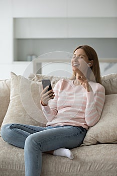 Cheerful woman listening to ambient music from small wireless earphone