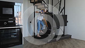 Cheerful woman listens to music while doing housework. A young woman is cleaning and dancing with a vacuum cleaner in