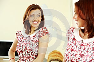 Cheerful woman looking on her reflection in the mirror