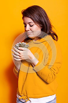 Cheerful woman looking at pot with green plant in hand