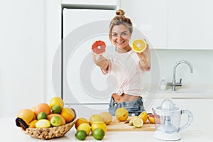 Cheerful woman with a lot of citrus fruits during fresh juice preparation at home