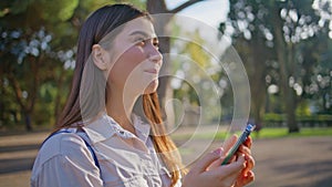 Cheerful woman messaging cellphone in park portraying happiness in digital age.