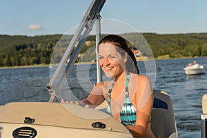 Cheerful woman navigating powerboat in summer