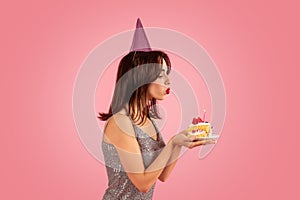 Cheerful woman in a party mood wearing a shiny dress and a party hat